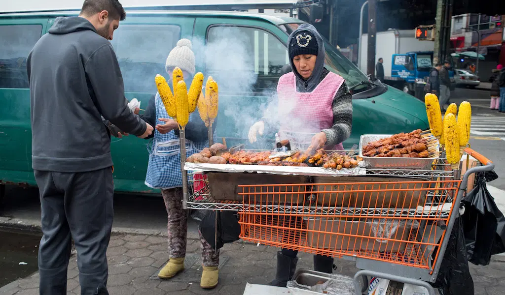Street vendor in NYC serving food from a makeshift grill